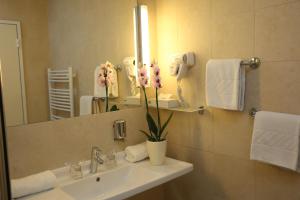 a bathroom with a sink with a vase with flowers on it at Hotel Draganic in Draganići +8 photos