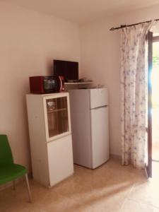 ブドーニにあるResidence Colle Maiorcaの小型冷蔵庫、緑の椅子が備わる客室です。