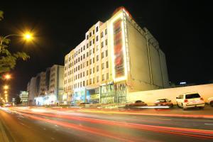 uma rua da cidade à noite com edifícios e carros em City Rose Hotel Suites em Amã