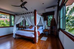 a bedroom with a canopy bed and windows at Stunning villa with ocean views and free car in Lamai