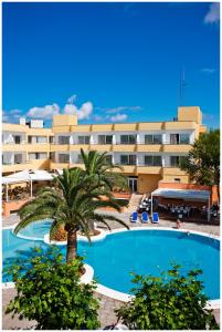 a large hotel with a palm tree and a swimming pool at Sagitario Playa in Cala Blanca