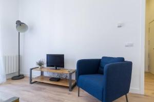 a living room with a blue chair and a table with a television at Marvelous Apartment of 3 Bedrooms near La Latina by Batuecas in Madrid