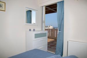 a white bedroom with a view of a balcony at Catherine's Comfort Apartment Νο3 in Lavrio