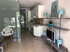 cocina con armarios blancos y TV en una habitación en PUERTO BANUS CRYSTAL Suite, en Marbella