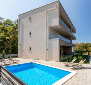 ein Haus mit einem Swimmingpool vor einem Gebäude in der Unterkunft Villa Neda in Malinska