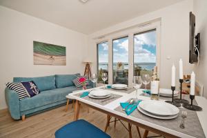 sala de estar con mesa y sofá azul en BlueApart Apartamenty Na Plaży Jastarnia en Jastarnia