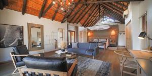 uma grande sala de estar com um sofá azul e cadeiras em Nkala Safari Lodge em Matlhagame