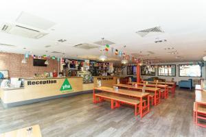 a restaurant with wooden tables and red chairs at YHA London Central in London