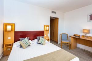 a bedroom with a bed with a desk and a chair at Hôtel Restaurant Splendid Camargue in Le Grau-du-Roi