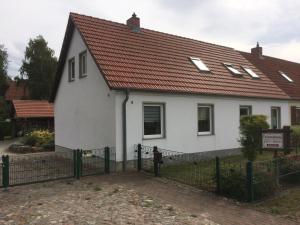 une maison blanche avec un toit rouge et une clôture dans l'établissement FeWo Karnitz/Rügen, à Karnitz