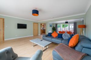 a living room with blue couches and orange pillows at 4 Kinnessburn Cottages in St. Andrews