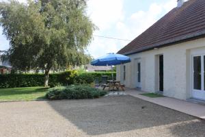 um pátio com um guarda-chuva azul ao lado de uma casa em Gîte La Presqu'île em Bricqueville-sur-Mer