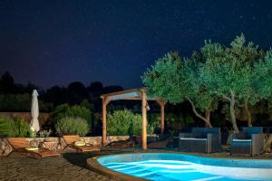 a swimming pool at night with chairs and an umbrella at Villa Oxa Dreamland in Stari Grad