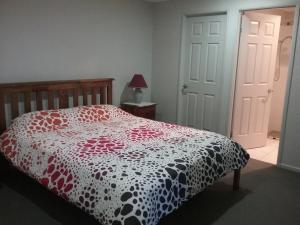 a bedroom with a bed with a red and white comforter at Banksia Apartment in Maryborough