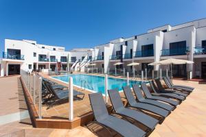 a row of lounge chairs next to a swimming pool at TAO El Cotillo - VV in El Cotillo