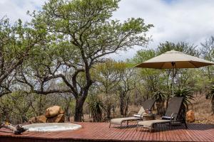 a table with an umbrella and two chairs on a deck at Mpeti Lodge in Mkuze