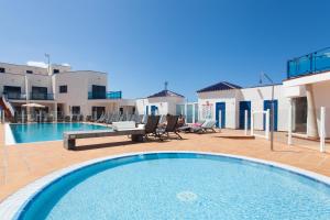 a large swimming pool with chairs and a house at TAO El Cotillo - VV in El Cotillo