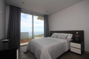 Un dormitorio con una cama y una ventana grande. en Villa Pinheira II, en Estreito da Calheta