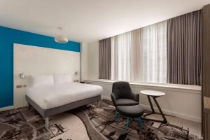 a hotel room with a bed and a chair at ibis Styles Glasgow Central in Glasgow