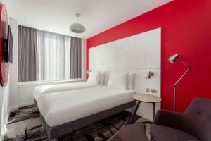a bedroom with a white bed and a red wall at ibis Styles Glasgow Central in Glasgow