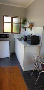 a kitchen with a counter with a microwave and a chair at Cobie Apartment in Stellenbosch