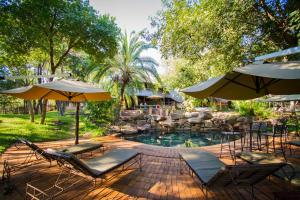 uma piscina com cadeiras e guarda-sóis num quintal em Lokuthula Lodge em Victoria Falls