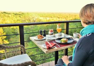 a woman sitting at a table with food and drinks at Victoria Falls Safari Club in Victoria Falls