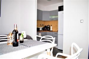 Biała kuchnia ze stołem i białymi krzesłami w obiekcie Apartament Fibra Cortado w Rybniku