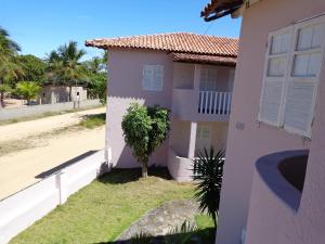 una casa blanca con un árbol en el patio en Residencial Bahia Sol, en Nova Viçosa