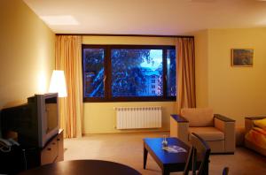 a living room with a tv and a couch and a table at Royal House Apartments TMF in Pamporovo