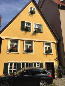 a black car parked in front of a yellow house at Lindes Ferienwohnung in Dinkelsbühl