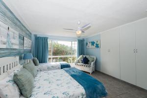 een slaapkamer met een bed, een bank en een raam bij Kenwyn on Sea 308 in Ballito