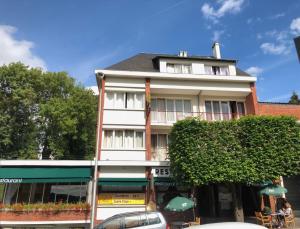 un bâtiment blanc au coin d'une rue dans l'établissement Logis Terrasse Hôtel, à Lisieux