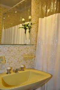 baño con lavabo amarillo y jarrón con flores en Petit Recoleta Suites en Buenos Aires