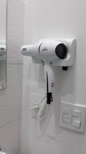 a white hair dryer hanging on a wall at Flats Cavalinho Branco 405 ou 603 in Águas de Lindoia