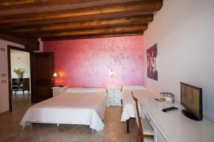 a bedroom with two beds and a desk with a television at Corte In Fiore in Ardea
