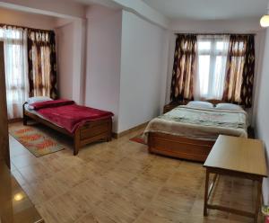 Un dormitorio con 2 camas y un banco. en Deki Lodge, en Kalimpong