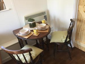 drewniany stół z dwoma krzesłami i dwoma kubkami na nim w obiekcie Little Woodacott w mieście Barnstaple