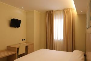a hotel room with a bed and a desk and a window at Hotel Ancora in Pontecagnano