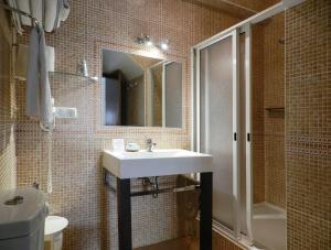 uma casa de banho com um lavatório, um chuveiro e um espelho. em Residencia Julio em Sagres