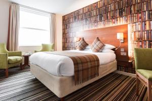 a hotel room with a large bed and bookshelves at ABode Canterbury in Canterbury