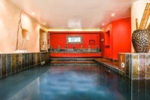 a swimming pool in a room with red walls at Hôtel Spa Mendi Alde in Ossès