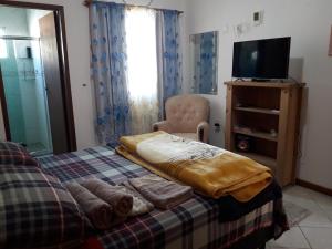 1 dormitorio con 1 cama, TV y silla en Suite master no caminho do mar- Norte de Floripa, en Florianópolis