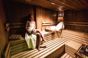 a woman sitting in a sauna with a man sleeping at Hotel Grand in Žilina