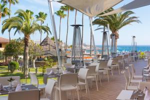 una fila de mesas y sillas en un complejo con palmeras en Iberostar Waves Bouganville Playa, en Adeje