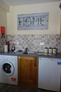 a kitchen with a sink and a washing machine at Old Mill Cottage in Swinford