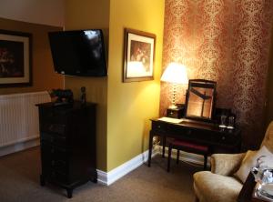 a hotel room with a tv and a dresser and a room at The Lion Hotel in Buckden