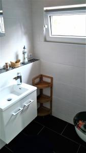 a white bathroom with a sink and a window at Bungalow Thiele in Döbeln