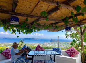 a man sitting on a couch under a pergola at Relais Bijoux Ischia in Ischia