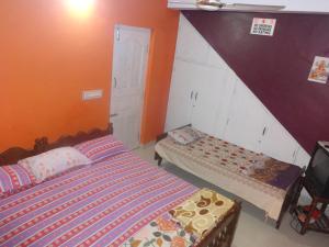 deux lits dans une chambre aux murs orange dans l'établissement Four Seasons Home Stay (1BDH), à Madikeri